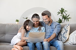 Happy family with kid girl having fun using laptop together