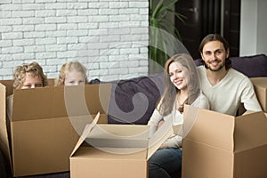 Happy family with kids and boxes on moving day, portrait