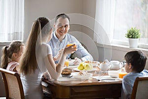 Happy family with kids having breakfast at home