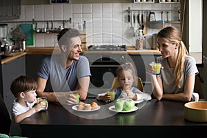 Happy family and kids having breakfast sitting at kitchen table