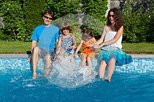 Happy family with kids having fun near pool on vacation