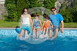 Happy family with kids having fun near pool on vacation