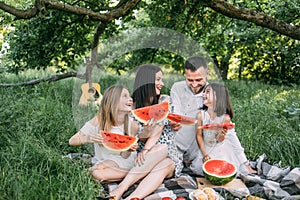 Happy family with kids having summer picnic at green park