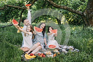 Happy family with kids having summer picnic at green park