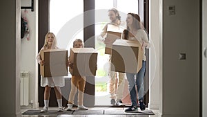 Happy family with kids holding boxes opening door entering house