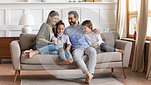 Happy family with kids relax on couch using cell