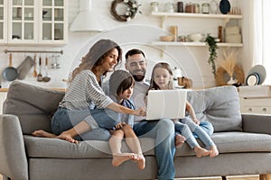 Happy family with kids sit on couch using laptop