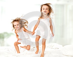 Happy family . kids twin sisters jumping on the bed, playing and laughing