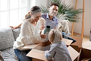 Happy family with kids unpacking boxes moving into new home