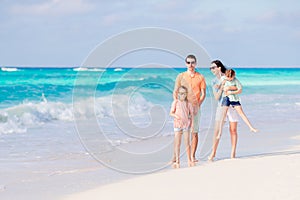 Happy family with kids walk on the beach at sunset