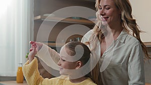 Happy family at kitchen Caucasian cute little child girl daughter hugging with mother holding by hands with mum dancing