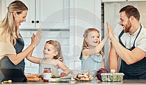 Happy family in kitchen, cooking with kids and high five with success, learning and nutrition with parents. Mom, dad and