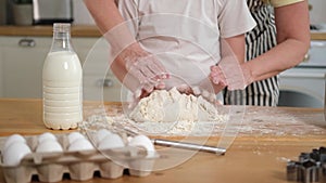 Happy family in kitchen. Grandmother granddaughter child hands knead dough on kitchen table together. Grandma teaching