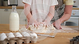 Happy family in kitchen. Grandmother granddaughter child hands knead dough on kitchen table together. Grandma teaching