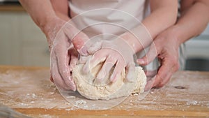 Happy family in kitchen. Grandmother granddaughter child hands knead dough on kitchen table together. Grandma teaching