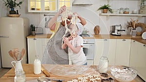 Happy family in kitchen. Grandmother granddaughter child knead dough in kitchen together. Kid girl and grandma have fun