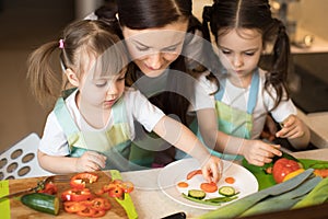 Happy family in the kitchen. Mom and daughters playing and having fun in the kitchen preparing.