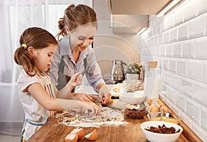 Happy family in kitchen. mother and child daughter baking cookies