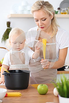 Happy family in the kitchen. Mother and child daughter cooking pasta