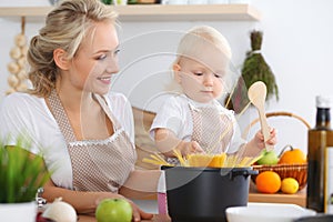 Happy family in the kitchen. Mother and child daughter cooking pasta