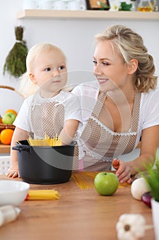 Happy family in the kitchen. Mother and child daughter cooking pasta