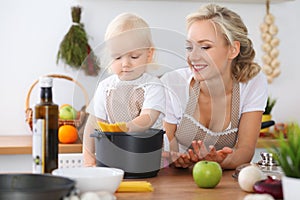 Happy family in the kitchen. Mother and child daughter cooking pasta