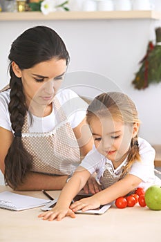 Happy family in the kitchen. Mother and child daughter make menue for cooking tasty breakfest in the kitchen. Little photo