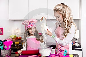 happy family in the kitchen. mother and child daughter preparing the dough