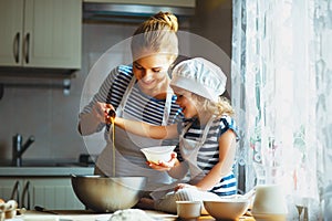 Happy family in kitchen. mother and child preparing dough, bake