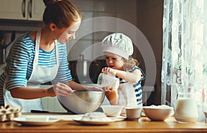 Happy family in kitchen. mother and child preparing dough, bake