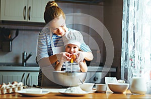 Happy family in kitchen. mother and child preparing dough, bake