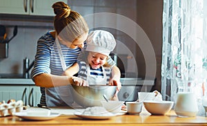 Happy family in kitchen. mother and child preparing dough, bake