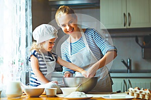 Happy family in kitchen. mother and child preparing dough, bake