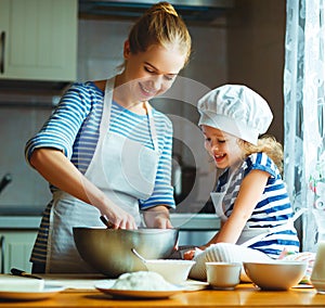 Happy family in kitchen. mother and child preparing dough, bake