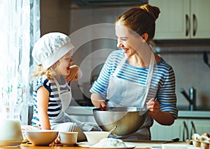 Happy family in kitchen. mother and child preparing dough, bake