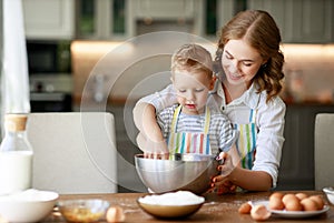 Happy family in kitchen. mother and child preparing dough, bake cookies