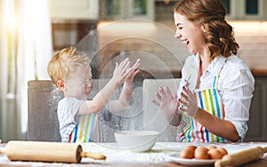 Happy family in kitchen. mother and child preparing dough, bake cookies