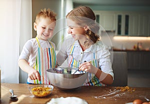 Happy family in kitchen. mother and child preparing dough, bake cookies