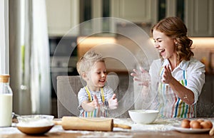 Happy family in kitchen. mother and child preparing dough, bake cookies