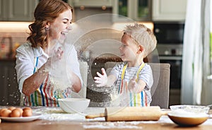 Happy family in kitchen. mother and child preparing dough, bake cookies