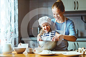 Happy family in kitchen. mother and child preparing dough, bake