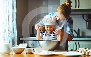 Happy family in kitchen. mother and child preparing dough, bake