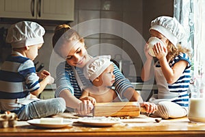 Happy family in kitchen. mother and children preparing dough, ba