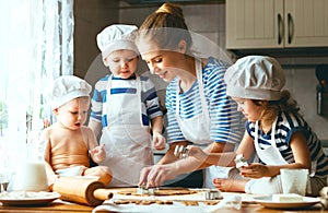 Happy family in kitchen. mother and children preparing dough, ba