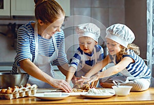 Happy family in kitchen. mother and children preparing dough, ba