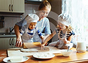 Happy family in kitchen. mother and children preparing dough, ba