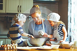 Happy family in kitchen. mother and children preparing dough, ba