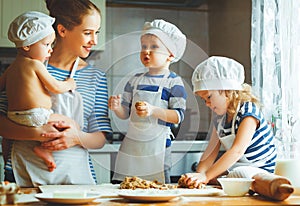 Happy family in kitchen. mother and children preparing dough, ba