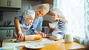 Happy family in kitchen. mother and children preparing dough, ba