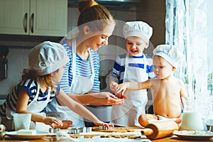 Happy family in kitchen. mother and children preparing dough, ba